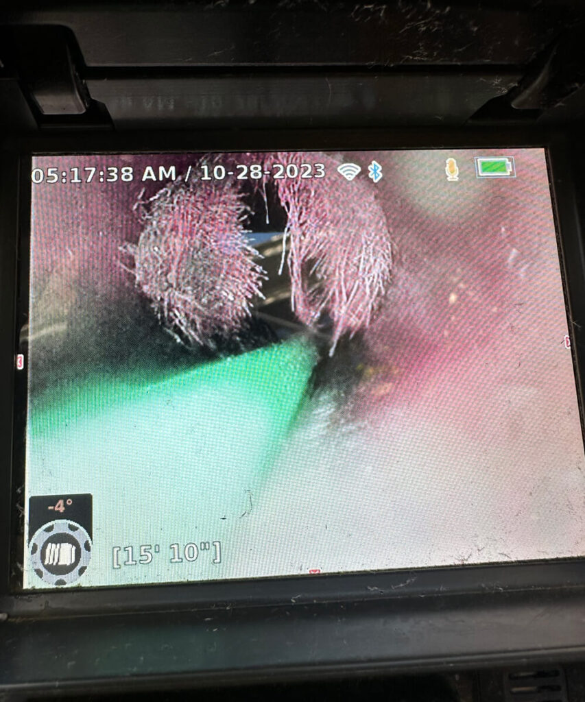 A screen displays a sewer line inspection camera's view.